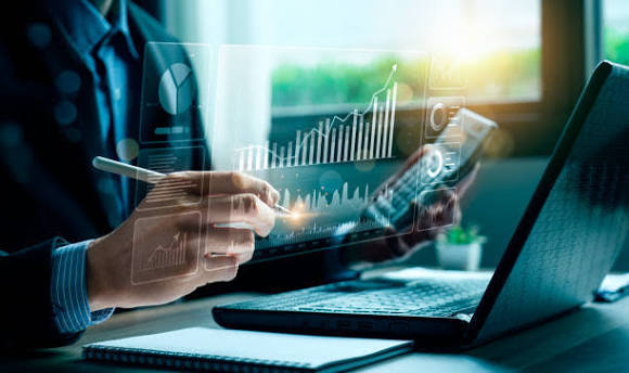 A finance desk with charts above a laptop